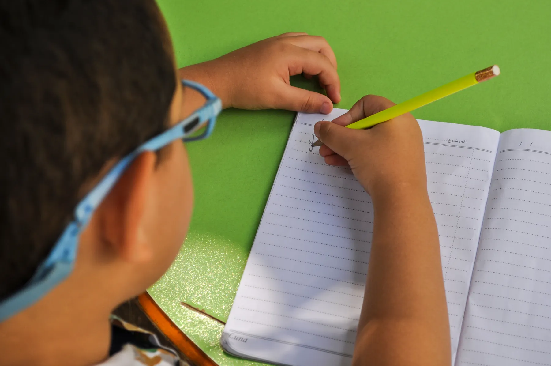 A child writing with a pencil in a notebook