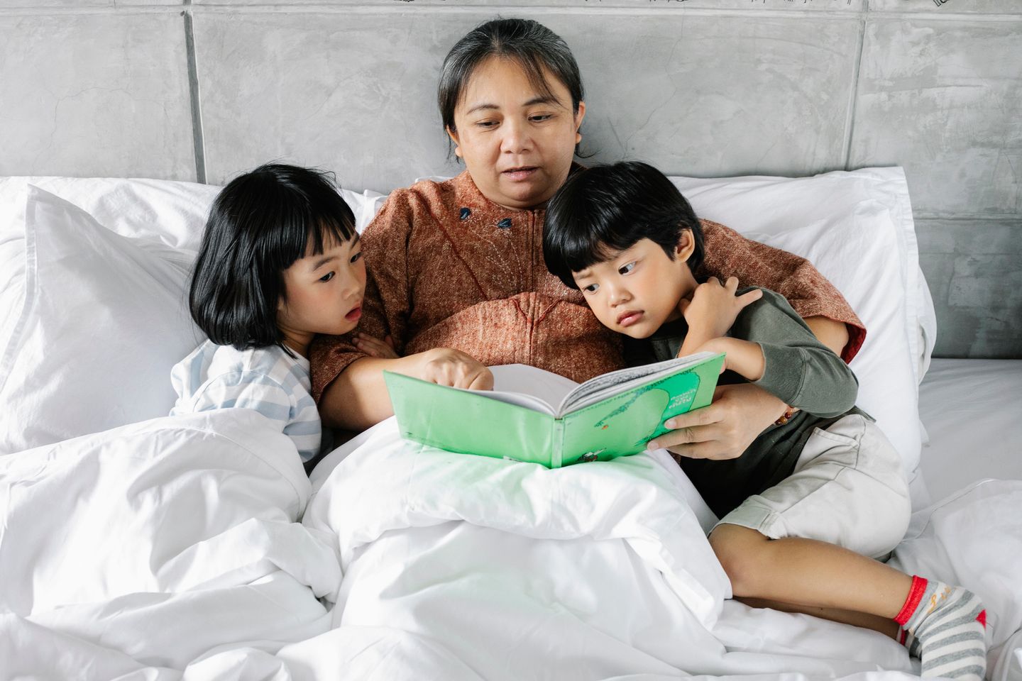 妈妈和两个孩子在客厅一起阅读绘本