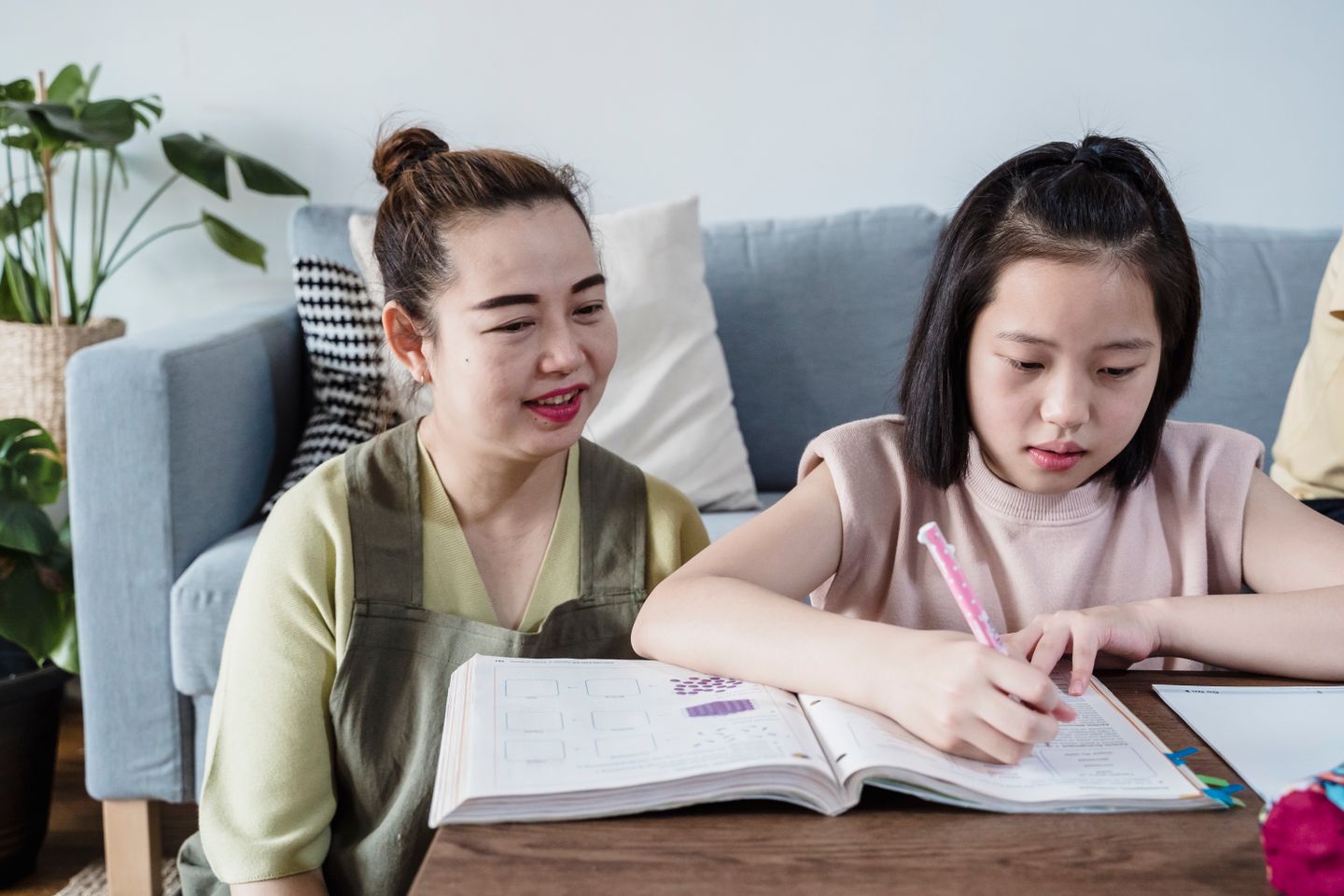 妈妈陪伴女儿在书桌前写字，孩子专注学习